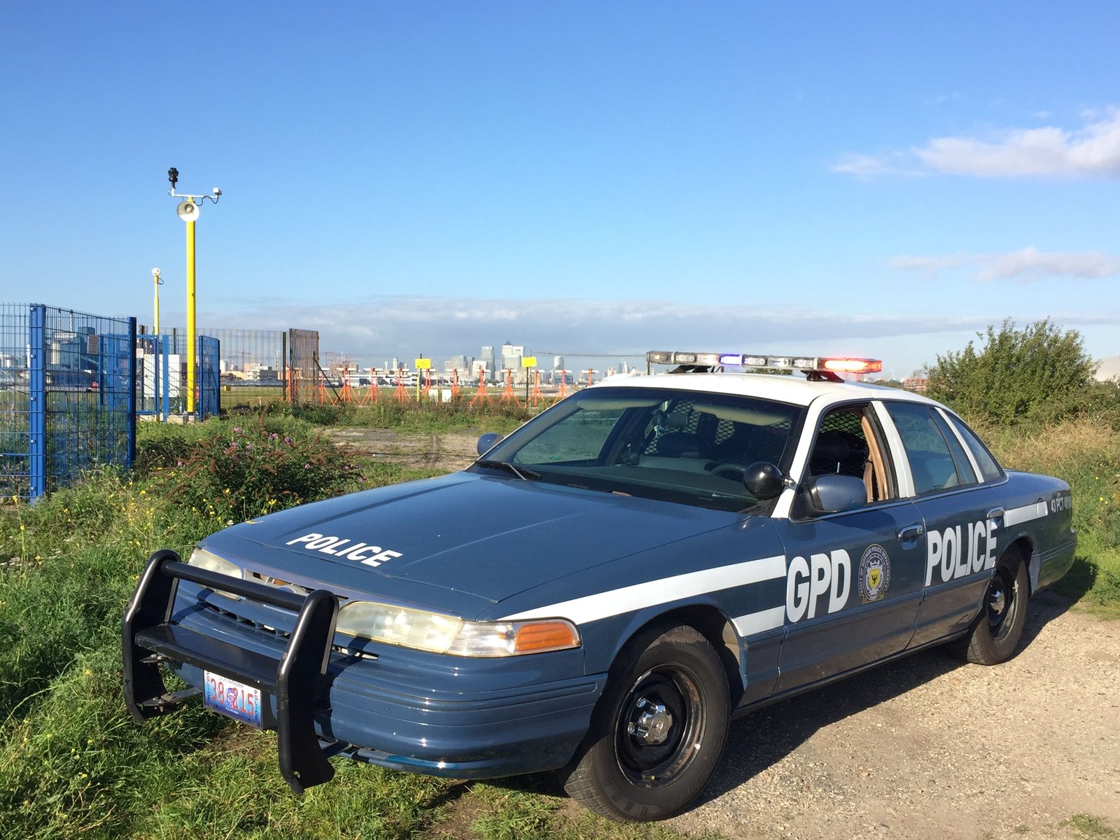 The Gotham Police Ford Crown Victoria in its earlier navy Dark Knight-era livery, with the London skyline behind