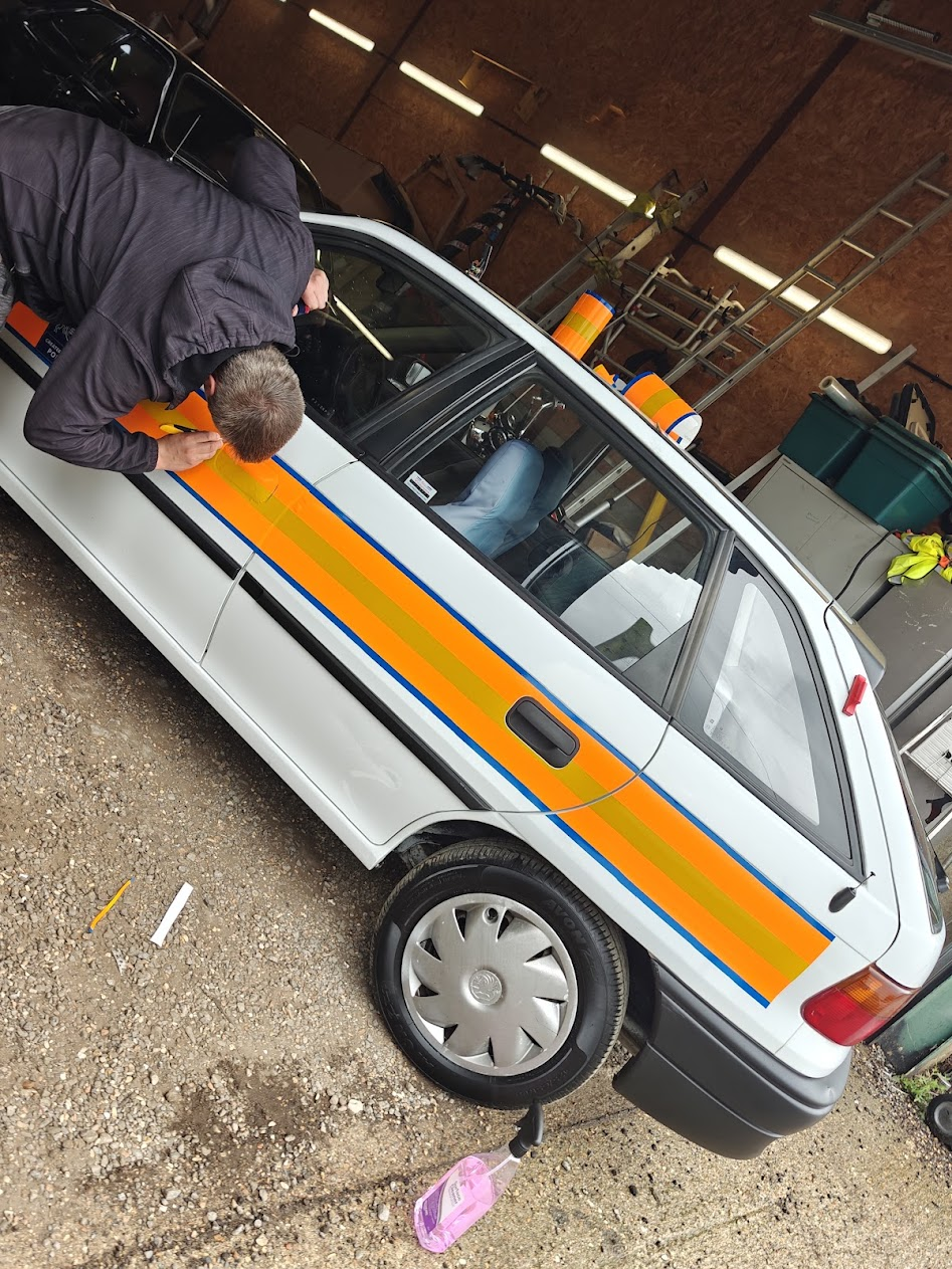 Reflective livery stripes being hand-applied to a vehicle in-house