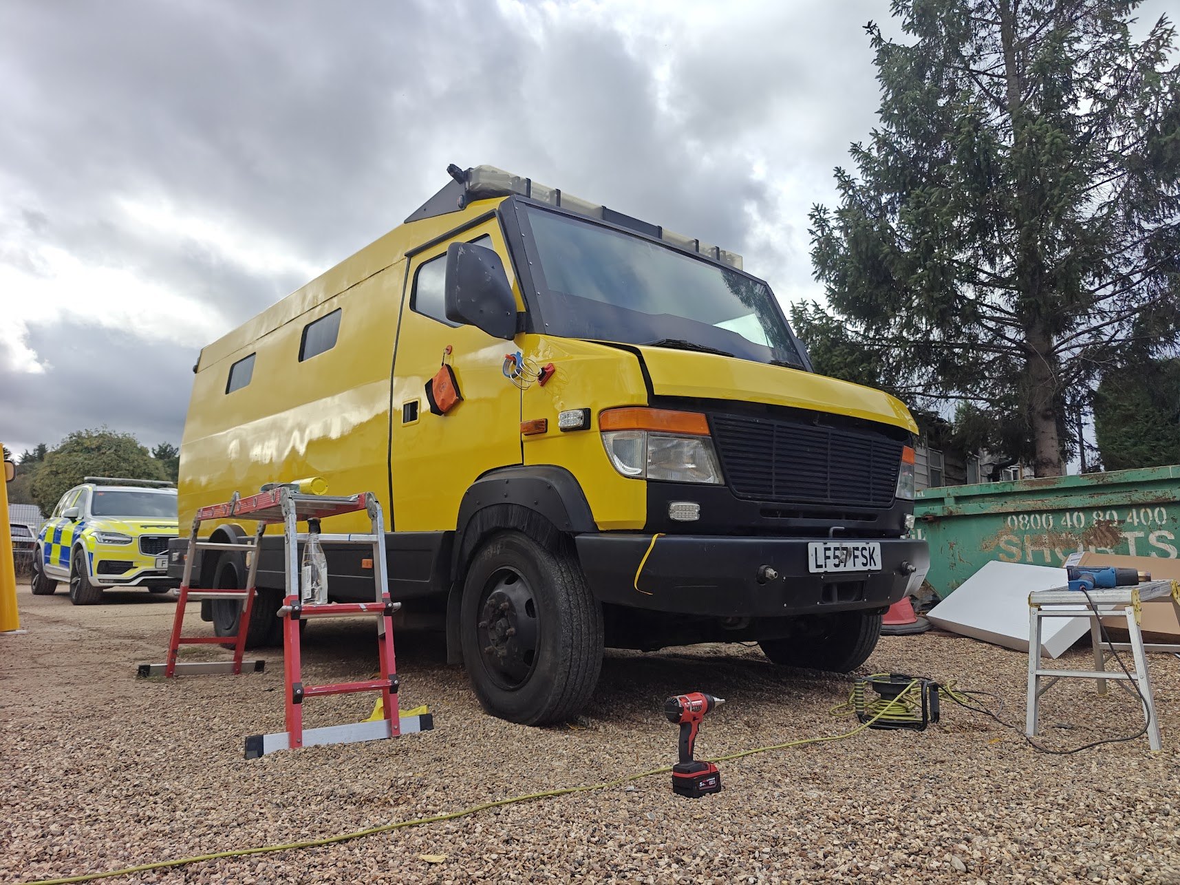 A van being prepared and wrapped at the Klassic Garage workshop, with a liveried police car in the background